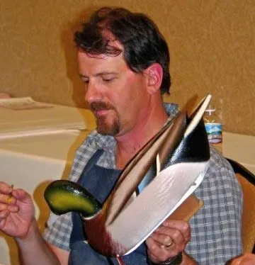 Robert meticulously painting a wooden duck decoy, showcasing his craftsmanship. The image highlights the artistry involved in decoy creation.